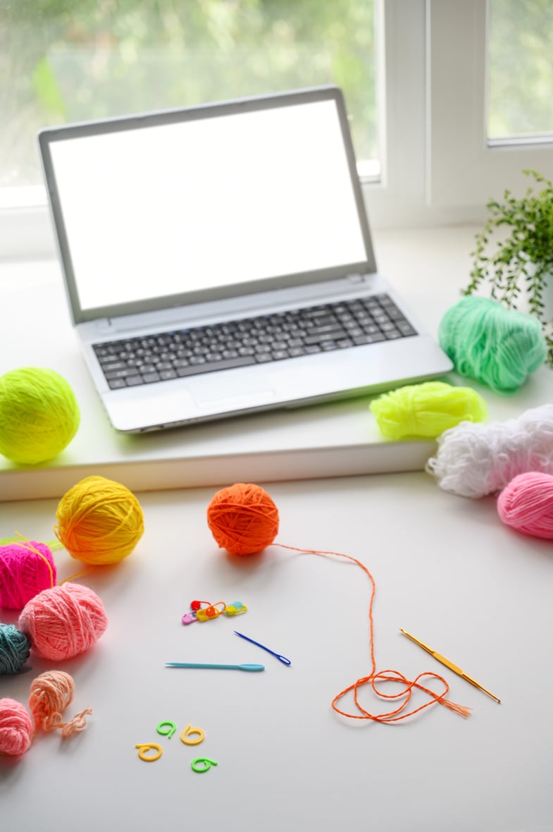 Online learning concept. Crochet accessories and laptop on the windowsill.